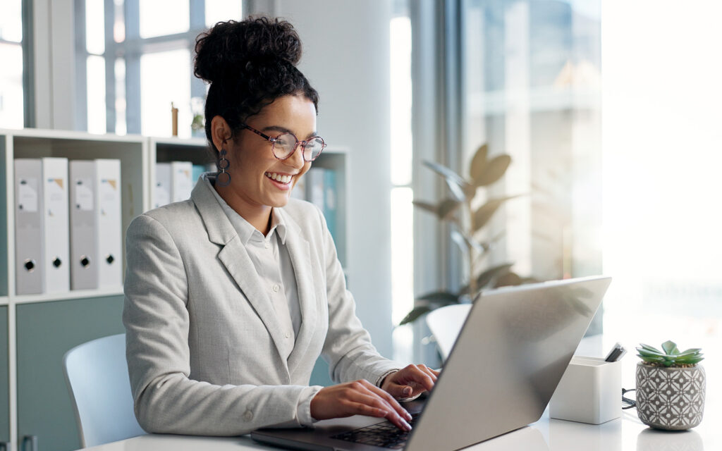 Side view of woman smiling at laptop